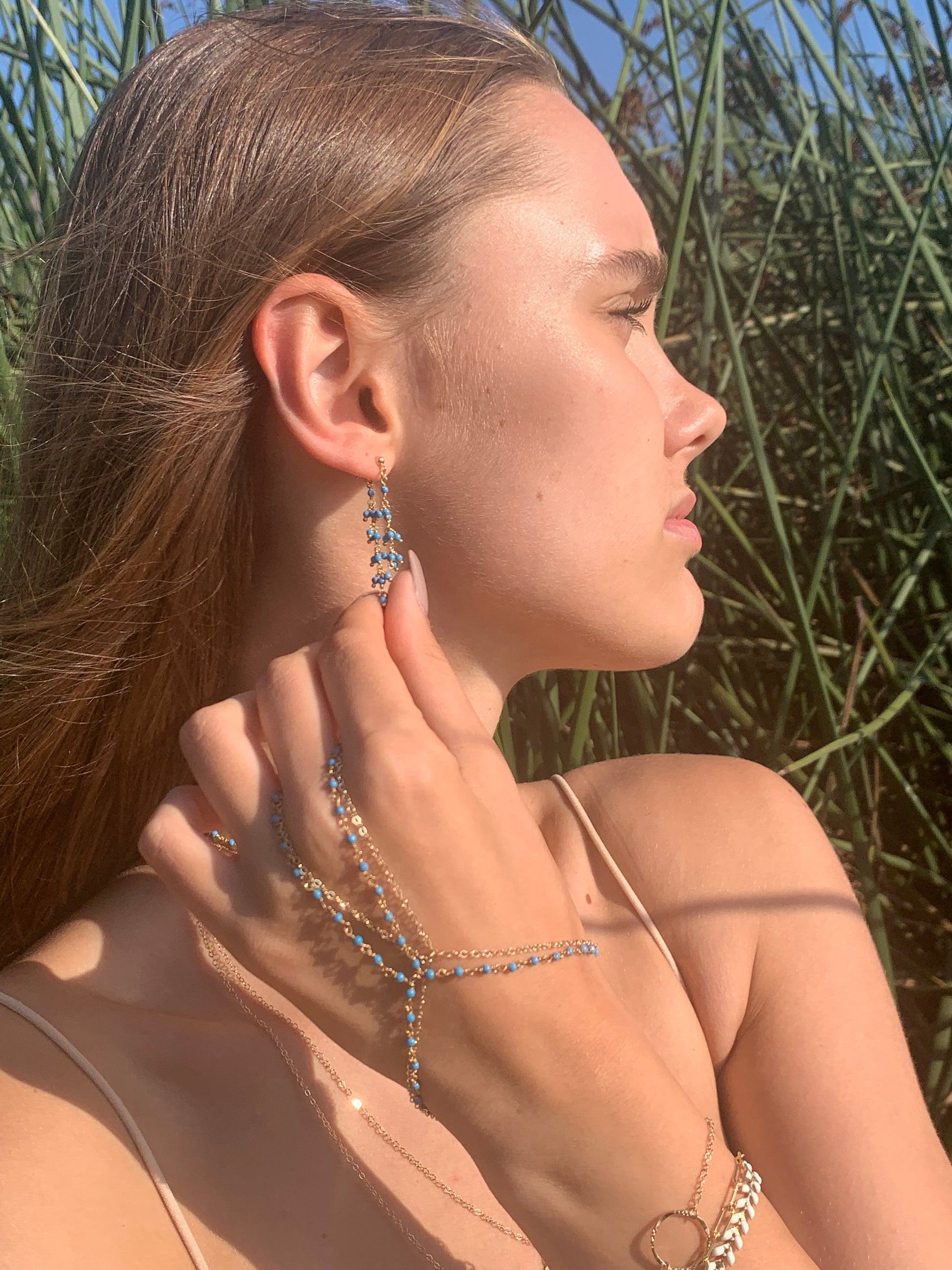 The turquoise handchain is layered with a matching gold handchain. Check out the turquoise earrings too! Chain by Lauren