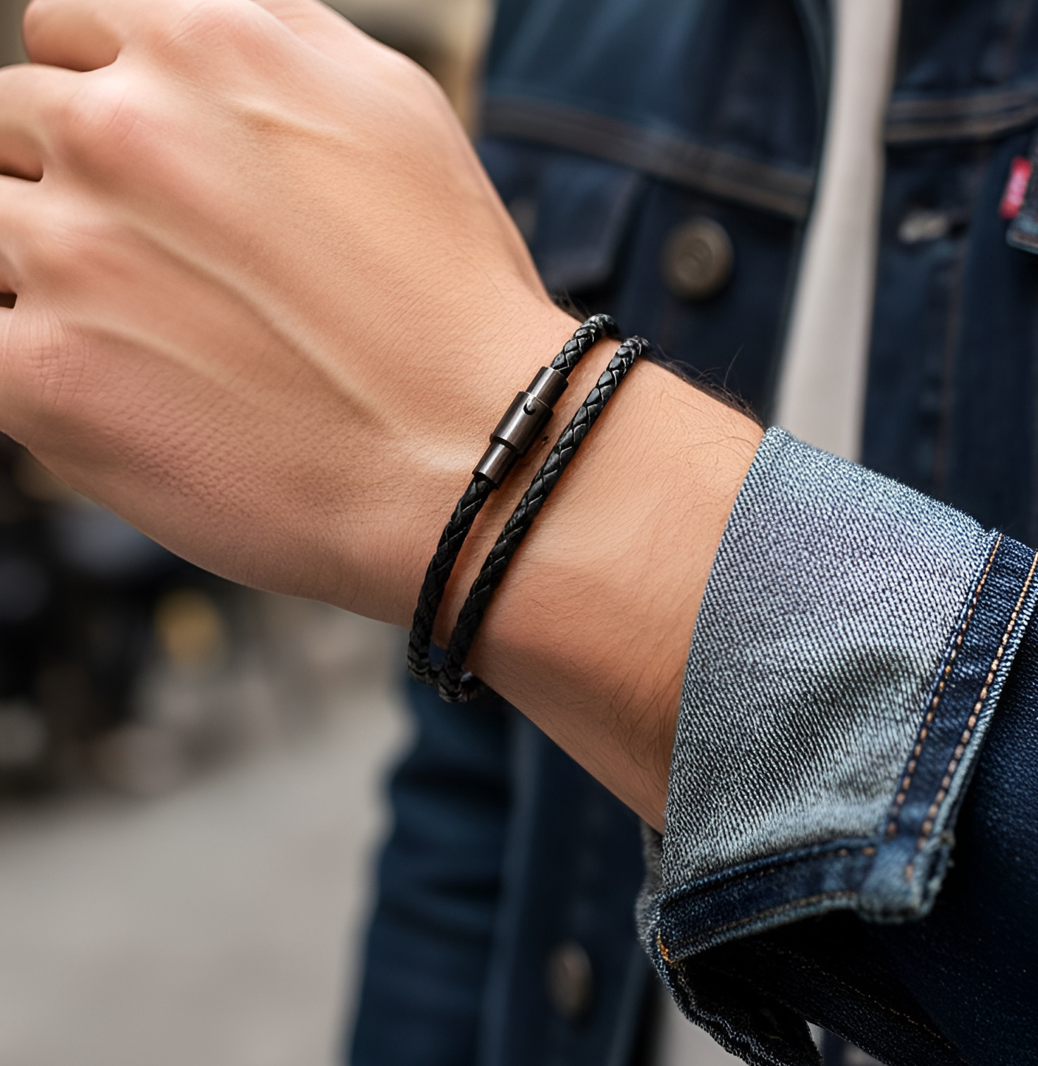 Close-up of a men's black leather wrap bracelet wearing a black braided bracelet.